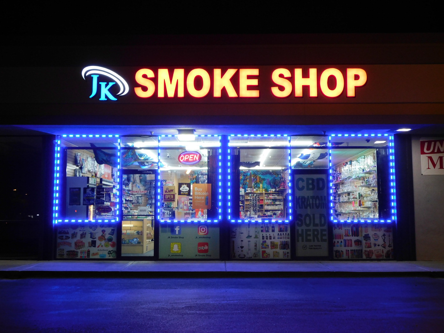The JK Smoke Shop storefront illuminated at night